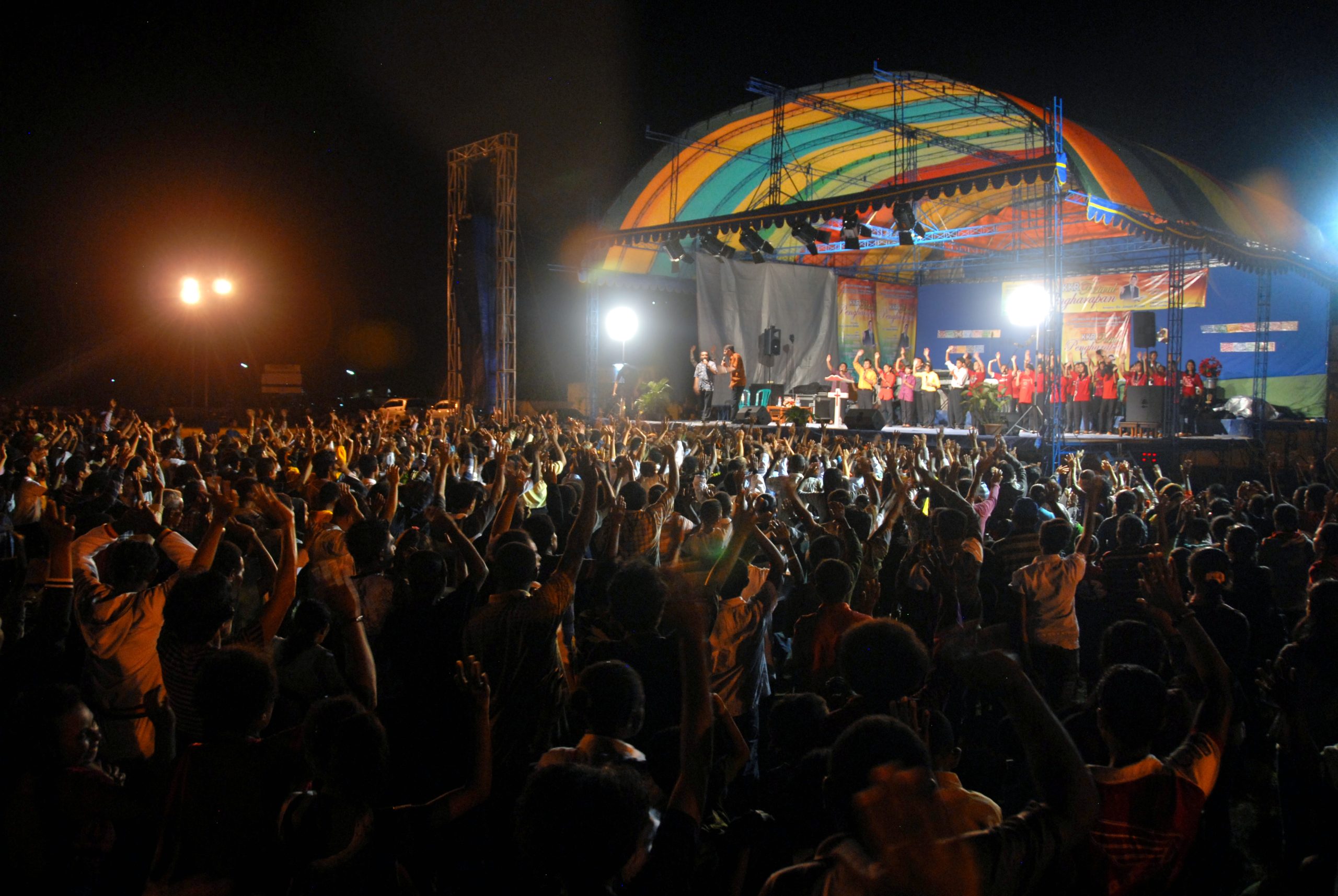A large crowd gathered in front of a lit stage at an evening Hope Festival